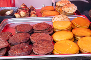 Grilled burger patties and smoked cheese on display.

