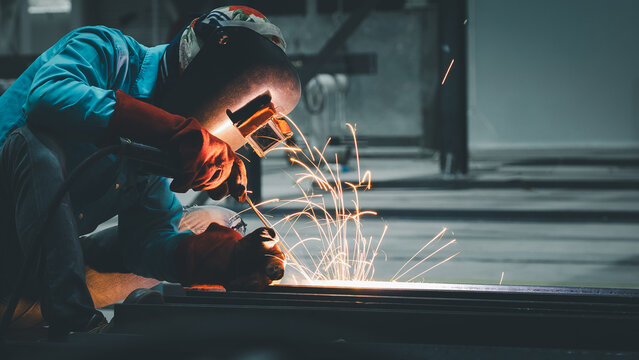 A skilled worker practices welding techniques, producing bright sparks while shaping metal materials. This activity takes place in an industrial workshop during the evening hours - Powered by Adobe