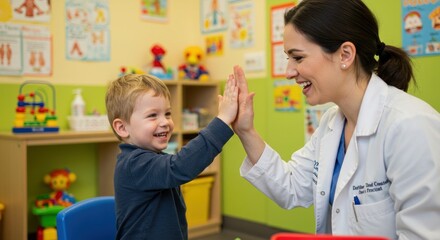 Young boy and woman giving each other a highfive in a brightly colored playroom