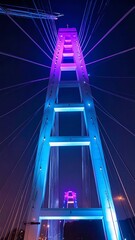 Fototapeta premium A vibrant nighttime view of a illuminated cable-stayed bridge pylon, showcasing striking gradient lighting effects.
