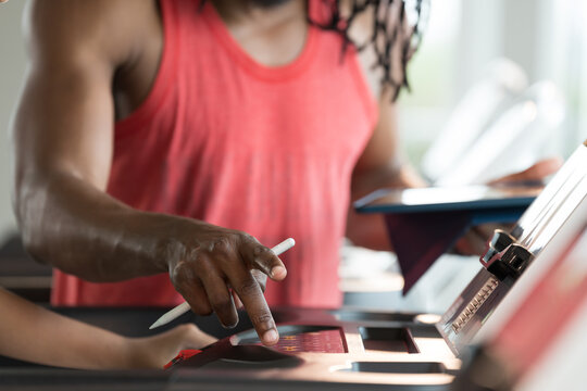 African American young girl and coach or personal trainer teaching and discussing on digital tablet during exercising, running on treadmill in gym. Health care, workout and cardio concept