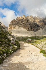 Hiking trail around Drei Zinnen mountains in Dolomites, Italy. Breathtaking alpine landscape with a hut in the distance, summer, clear weather, majestic peaks.