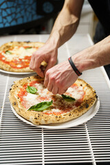 Chef garnishing pizza with fresh basil leaves