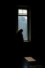 Fototapeta premium Silhouette Person Near Open Window Overlooking Distant Cityscape