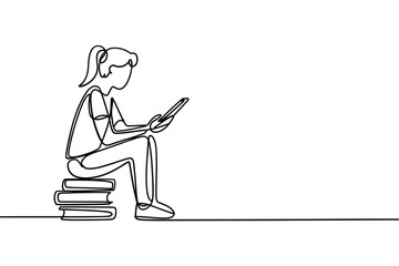 Young woman sitting on books reading on a tablet device