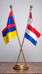 Two national flags, the flag of the Tibetan people and the flag of the Kingdom of the Netherlands, positioned on a brass stand against a neutral backdrop, showcasing a diplomatic or international...