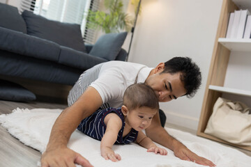 Fototapeta premium A man is holding a baby and playing with the baby happily. The atmosphere is warm and full of love as the man and the baby share a special moment together.