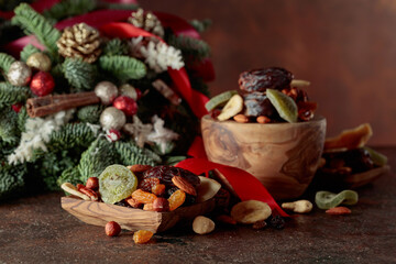 Dried fruits and nuts with Christmas wreath on a brown vintage table.