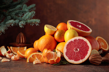 Citrus fruits and branch of spruce on a brown background.