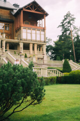 Elegant Wooden Mansion Amidst Lush Greenery and Stone Balustrade