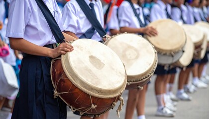 Traditional school parade with students in uniforms carrying banners and drums.