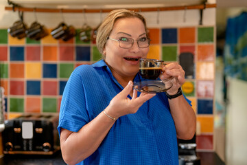 Woman enjoys a cup of coffee in a colorful kitchen while showcasing excitement and joy as she savors her beverage moment