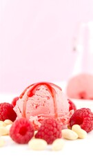 Pink ice cream scoop drizzled with raspberry syrup, surrounded by raspberries and peanuts