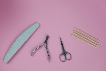 Set of tools for manicure and nail design with glitter on a pink background.