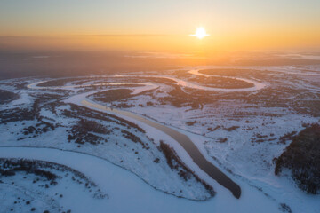 Snow-covered landscape with winding river at sunrise