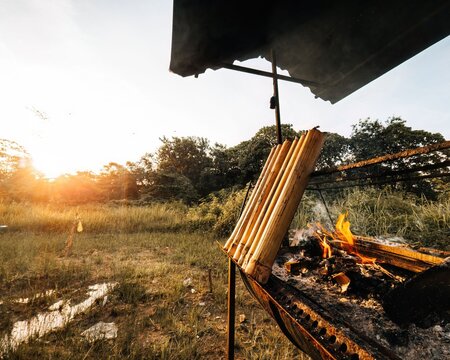 Fire burning the wood while cooking lemang at sunset.