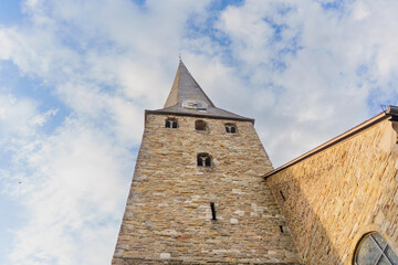 Fototapeta premium Historic Stone Church Tower Under Cloudy Sky in Hattingen Germany