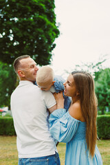 Fototapeta premium This heartwarming moment captures the sheer joy of a family as the parents engage playfully with their child outside, enjoying the beauty of a vibrant, lush green environment that surrounds them