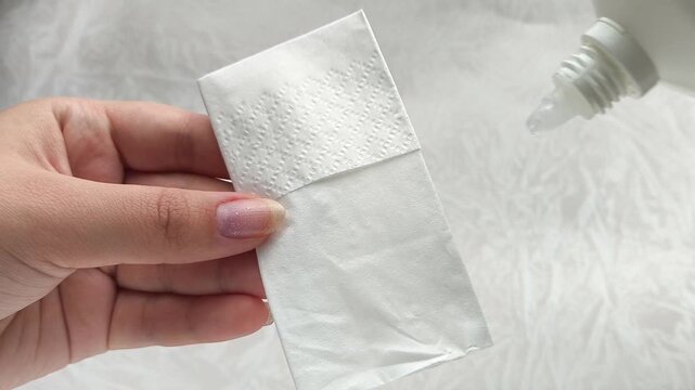 A woman pours liquid hydrogen peroxide from a bottle onto a napkin Wound treatment concept