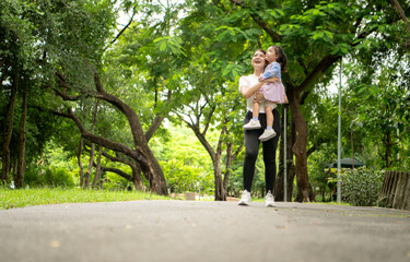 Fototapeta premium Mother and daughter jogging together in the park, promoting healthy lifestyle and family bonding