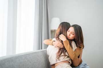 In a contemporary, relaxed environment, two women warmly share a supportive and heartfelt hug