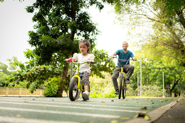 Obraz premium Grandfather and little girl to ride balance bike in park on the holidays of the week