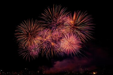 Fototapeta premium Fireworks display lights up the night sky over the city skyline with vibrant colors and spectacular patterns
