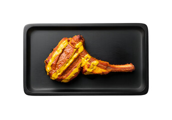 A grilled meat dish, richly seasoned and adorned with a vibrant mustard-yellow sauce, presented on a sleek black tray.