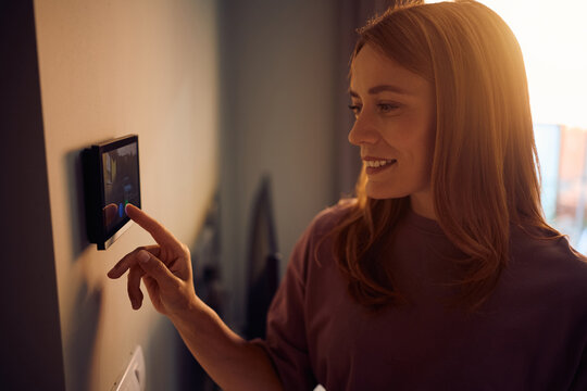 Happy woman using video intercom in modern home.