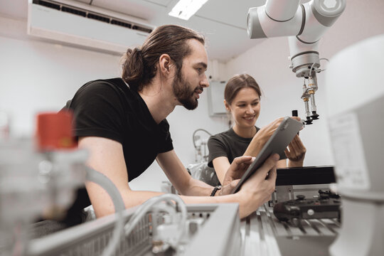 Industrial Robotics program university students learning education mechanical assembly with Robot Universal Training Platform robot arm simulation model in engineering lab classroom.