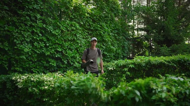 Gardener using professional leaf blower to clear foliage from shrubs and plants. Essential landscape maintenance for pristine garden design.