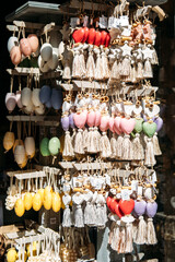 Colorful hanging soaps in heart, oval, and star shapes with tassels on display at an outdoor market stall. Decorative bath products, artisanal soapmaking, handcrafted gifts, sensory experience