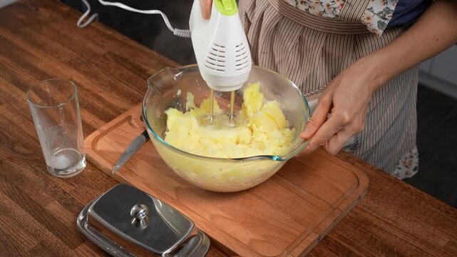 Woman using mixer to whip potatoes for mashed potatoes. Close-up, creamy.