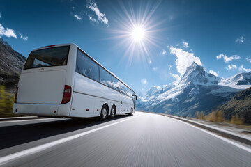 Obraz premium White coach bus driving on a sunny mountain road with snow-covered peaks under a clear blue sky