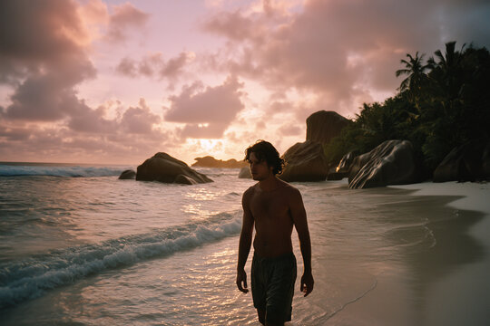 Young man walking on a tropical beach at sunset with dramatic clouds and rocky shoreline - Powered by Adobe