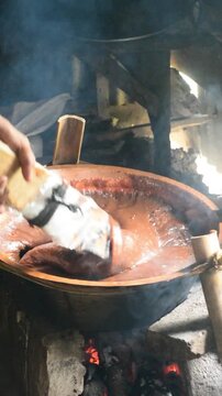 Traditional dodol making process in Indonesia using a large cooking pan and continuous stirring.