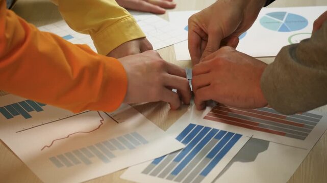 Collaborating over business chart and graph with team around table showing hand gestures during meeting for strategy and analysis with scattered chart document and puzzle piece for collaboration