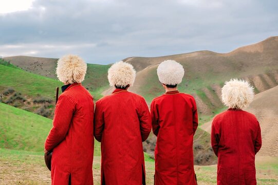 Traditional Turkmen Men in Red Robes and Fur Hats in Nature