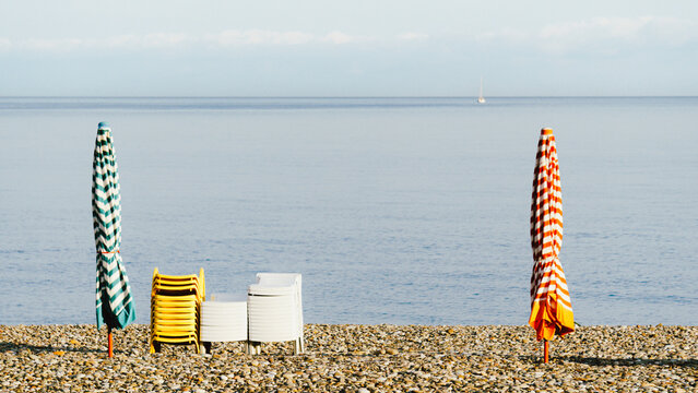 striped beach umbrellas with stacked yellow chairs