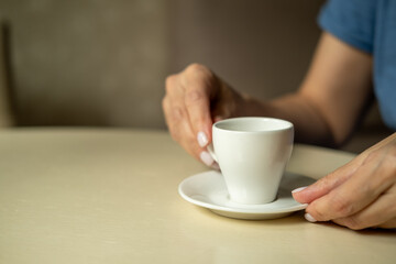  Close up of female hands holding little white cup of tea or coffee.