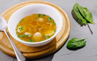 Delicious homemade soup served in a white bowl on a wooden board