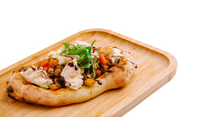 Delicious flatbread topped with vegetables and feta cheese served on wooden tray