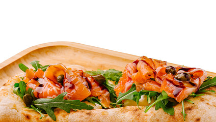 Gourmet flatbread topped with smoked salmon and arugula served on a wooden tray