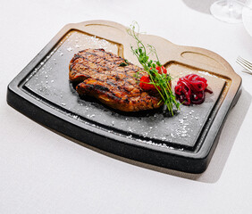 Grilled steak served on a sizzling stone plate with garnish