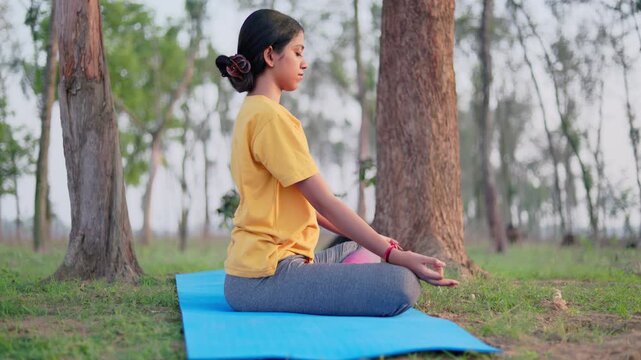 Tranquility woman meditating in the forest during sunrise, maintaining healthy lifestyle.