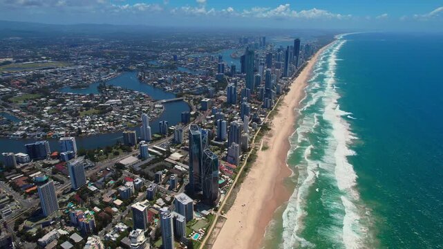 Aerial panorama of Gold Coast showcasing endless sandy beaches, the ocean, towering skyscrapers, and low-rise suburbs. Bright summer day with vibrant colors and stunning coastal views.