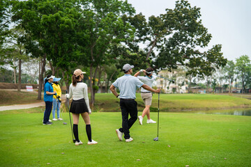 Obraz premium Group of young pro golfers swings their club on scenic golf course.