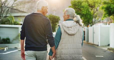 Senior couple, holding hands and walking with back in neighborhood for romance, date or bonding. Elderly, man and woman strolling in street or road for mobility, commitment or retirement together