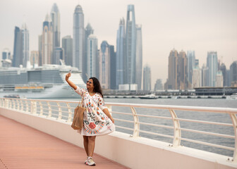 Dubai Marina background with Cruise sailing in the sea and a young tourist woman clicking photos, Dubai luxury travel and lifestyle stock photos