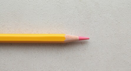 Yellow and Pink Colored Pencil on Textured Gray Background, Closeup View.